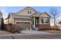 Inviting home with a two-car garage, stone accents, and neutral-colored siding surrounded by a well-kept lawn and street view at 9587 Kentwick Cir, Englewood, CO 80112