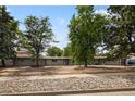 Single story home featuring a well-manicured yard with mature trees and rock ground covering at 2175 S Joliet St, Aurora, CO 80014