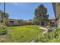 Expansive backyard with lush green grass, mature trees, and a patio seating area at 2844 Bellaire St, Denver, CO 80207
