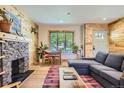 Cozy living room featuring a stone fireplace, wood paneling, and a comfortable gray sectional at 2844 Bellaire St, Denver, CO 80207