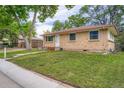 Cute brick home with a well-manicured lawn and a sidewalk leading to the front door at 5274 Alkire St, Arvada, CO 80002