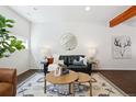 Cozy living room featuring a black leather sofa, round coffee tables, and rustic wood beam at 1711 Hooker St # 2, Denver, CO 80204