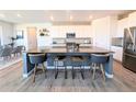 Modern kitchen boasts sleek white cabinets, stainless steel appliances, and a spacious center island with seating at 864 Clover Loop, Erie, CO 80026