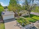Aerial view of a quaint home with a detached garage, driveway, and mature trees at 943 Pinon Ct, Longmont, CO 80504