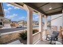 Inviting covered porch with sturdy columns, a rocking chair, and a view of the neighborhood street at 16317 Saint Paul St, Thornton, CO 80602