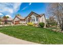 Well-maintained lawn and landscaping surround this brick home featuring a three-car garage at 4532 Christensen Cir, Littleton, CO 80123