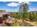 Inviting back deck with table and chairs offers scenic views of lush trees and beautiful natural surroundings at 8838 Hillview Rd, Morrison, CO 80465