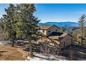 Scenic view of a mountain home with a large garage and picturesque mountain backdrop at 12933 Upper Ridge Rd, Conifer, CO 80433