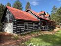Beautiful cabin with red metal roof, white-trimmed windows, and attached garage, nestled among tall pine trees at 9716 Canon Dr, Sedalia, CO 80135