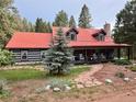 Charming cabin featuring a red metal roof, inviting front porch with rocking chairs, and a stone pathway at 9716 Canon Dr, Sedalia, CO 80135