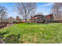 Expansive backyard showcasing lush green grass, a deck, and mature trees, perfect for outdoor activities at 8320 W Harvard Dr, Lakewood, CO 80227