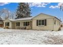 Charming single-story home with a brick facade, covered porch, and snow-covered yard at 3865 Independence Ct, Wheat Ridge, CO 80033