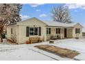 Charming single-story home with a brick facade, covered porch, and snow-covered yard at 3865 Independence Ct, Wheat Ridge, CO 80033