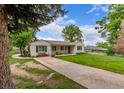 A charming white brick home with dark shutters, bench seating and a well-kept lawn at 3865 Independence Ct, Wheat Ridge, CO 80033