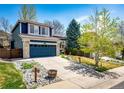 Charming two-story home boasts a blue exterior, stone accents, well-manicured lawn, and a blue garage door at 1941 Fox Fire St, Highlands Ranch, CO 80129