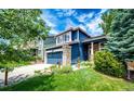 Beautiful home showcasing a well-maintained lawn, blue siding, stone accents, and a convenient two-car garage at 1941 Fox Fire St, Highlands Ranch, CO 80129