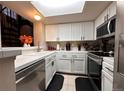 Bright kitchen with white cabinets and appliances, featuring a passthrough to the living area at 4933 S Carson St # 212, Aurora, CO 80015