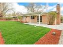 Spacious backyard featuring lush green grass, a covered patio, and wood mulch perimeter at 8487 W 62Nd Pl, Arvada, CO 80004
