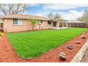 Expansive backyard with well-maintained lawn, wood mulch accents, and a cozy covered patio area at 8487 W 62Nd Pl, Arvada, CO 80004