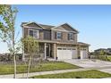 A daytime view of a two-story home showcasing a covered front porch and three-car garage at 7702 E 159Th Ave, Thornton, CO 80602