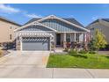 Charming single-story home featuring well-kept lawn, inviting porch, gray siding, and a two-car garage at 14066 Ivanhoe Ct, Thornton, CO 80602