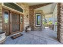 Inviting stone porch with a rustic wood door and views of the outdoor living space at 5275 Pinyon Jay Rd, Parker, CO 80134