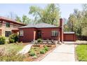 Cozy red brick home with green lawn, lush trees, garden and driveway to a detached garage at 650 Kearney St, Denver, CO 80220