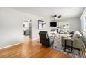 Cozy living room with hardwood floors, ceiling fan, and fireplace, adjoined to the kitchen area at 6513 Gray St, Arvada, CO 80003
