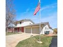 Side view of a two-story home with a spacious two-car garage, American flag, and nice yard at 1941 E 119Th Pl, Northglenn, CO 80233