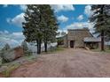 Stone home on a hill with a partial view and fronted by mature trees at 1150 Madge Gulch Rd, Sedalia, CO 80135