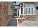 Close up of a well-maintained front door with stone details, flower pots, and a security system at 85 Willowleaf Dr, Littleton, CO 80127
