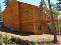 This two-story wooden home sits on a sloped lot, featuring modern windows and a balcony at 10178 Hutch Ln, Conifer, CO 80433