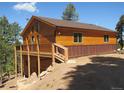 Wood cabin home featuring a walk out deck, brown shingles, and wood exterior against a blue sky at 10178 Hutch Ln, Conifer, CO 80433