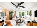 Cozy living room featuring a large fan, a white sectional, and tree views through large windows at 6512 Upham St, Arvada, CO 80003