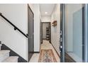 Bright entryway with white tiled floor, modern staircase, and coat rack offering a clean, contemporary aesthetic at 1287 Quitman St, Denver, CO 80204