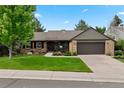 Inviting single-story brick home boasts a manicured lawn, mature trees, and an attached two-car garage at 7881 S Ivy Ct, Centennial, CO 80112