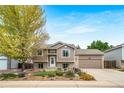 Inviting two-story home with tan siding, a well-kept lawn, and colorful flower beds enhancing curb appeal at 1482 S Pitkin Cir, Aurora, CO 80017