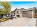 Well-maintained home featuring a spacious driveway, lush landscaping, and attractive tan exterior at 1482 S Pitkin Cir, Aurora, CO 80017