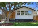 Charming single-story home featuring clean white stucco, dark trim, large shade tree and lawn at 3469 Benton St, Wheat Ridge, CO 80212