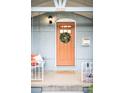 Charming front porch with peach-colored door and wreath, accented with a porch swing and potted flowers at 3425 W 34Th Ave, Denver, CO 80211