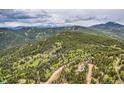 Scenic aerial view showcasing the natural beauty of the wooded land with rolling hills and snow-capped mountain backdrop at 266 Lodgepole Dr, Evergreen, CO 80439
