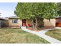 Charming brick home featuring a well-maintained lawn, mature tree and inviting front porch with red chairs at 2211 Lamar St, Edgewater, CO 80214
