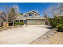 Inviting two-story house with a three-car garage, mature trees, manicured landscaping, and a concrete driveway at 10856 Parker Vista Ln, Parker, CO 80138