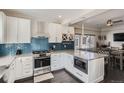 Bright open kitchen with island, stainless steel appliances, and adjacent dining area at 7998 E Vassar Dr, Denver, CO 80231