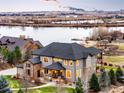 Captivating exterior shot of the home featuring stone accents, a covered porch, and beautiful lake views at 12648 Waterside Ln, Longmont, CO 80504