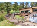 Beautiful home exterior with mature landscaping, a spacious deck, and relaxing hot tub at 187 Marion Dr, Evergreen, CO 80439
