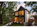 Modern two-story home featuring a unique black and white exterior, enhanced by lush trees and landscaping at 1117 S Madison St, Denver, CO 80210