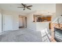 Open-concept living area featuring a cozy fireplace, a partial wall to the kitchen and carpeted floors at 7440 S Blackhawk St # 4-102, Englewood, CO 80112