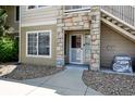 Welcoming condo front door with stone details and exterior stairway access at 9963 E Carolina Cir # 104, Aurora, CO 80247