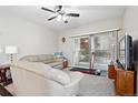 Bright living room with sliding glass doors to balcony and a ceiling fan at 9963 E Carolina Cir # 104, Aurora, CO 80247